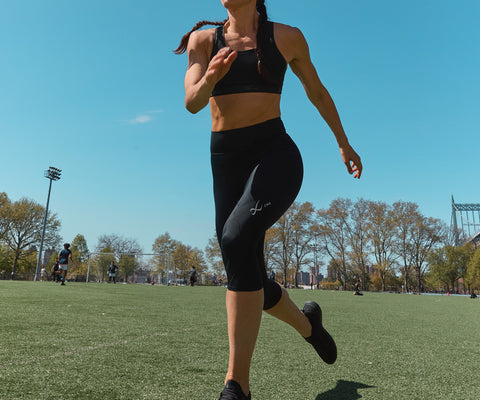 female doing a workout on a turf field wearing cw-x compression gear